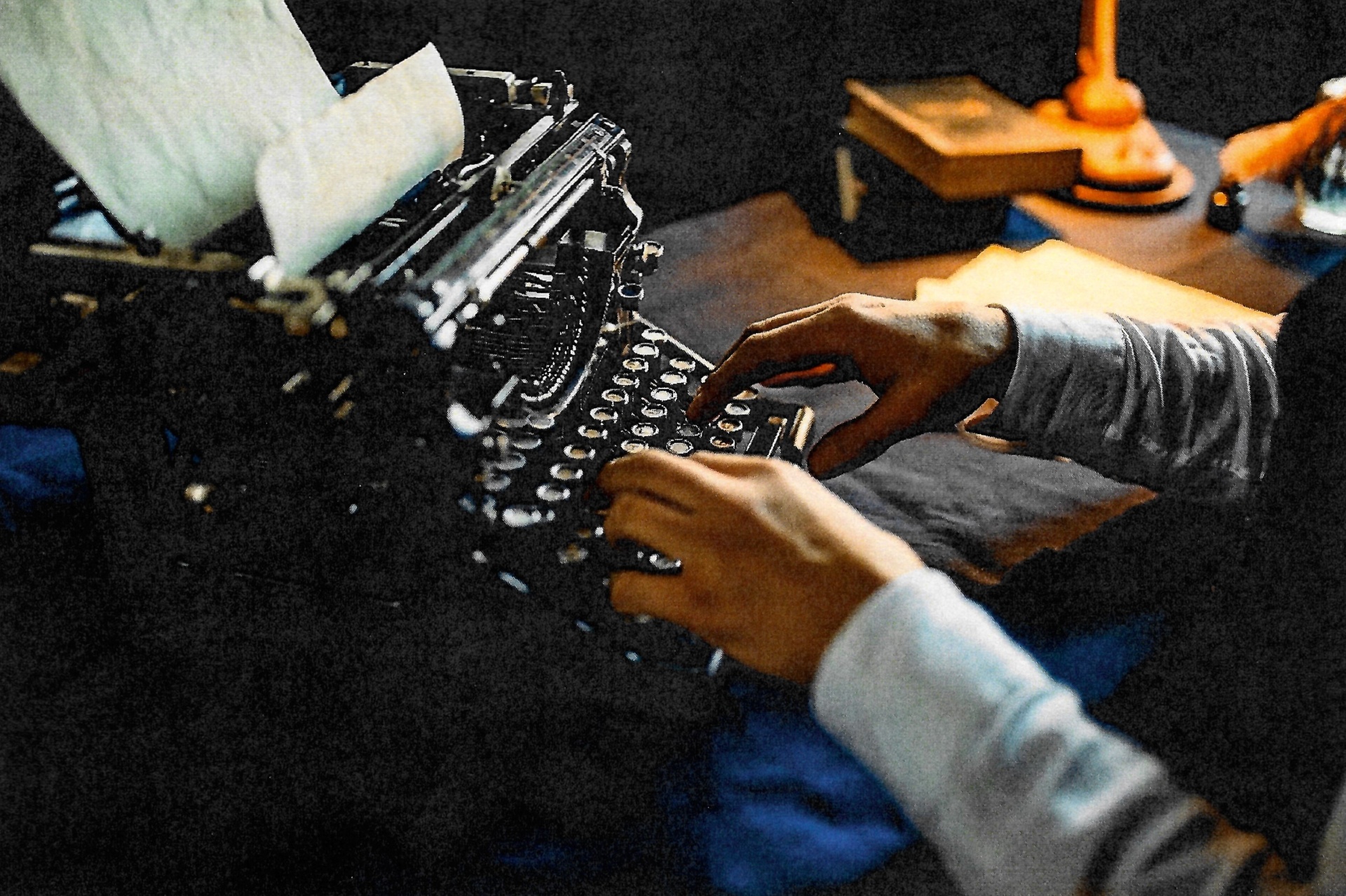 Hands typing on a vintage typewriter under warm lamplight